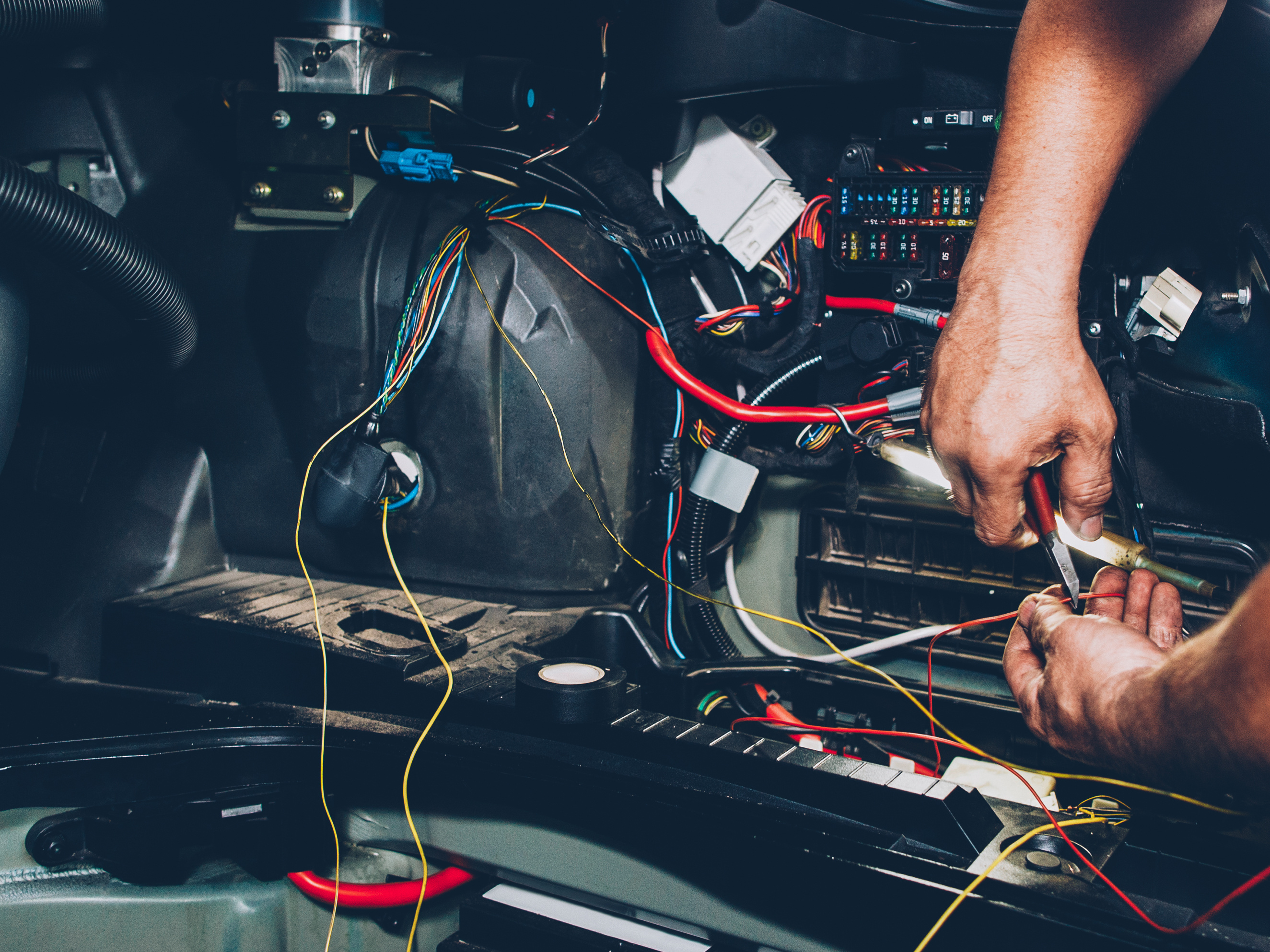 man working on wires for a car